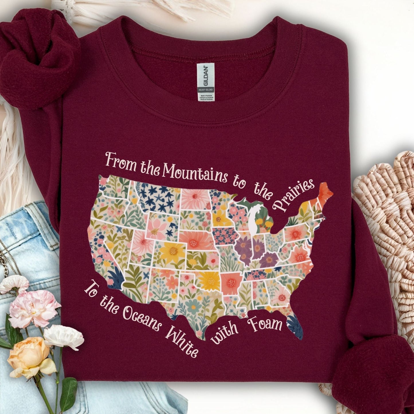 Maroon crewneck sweatshirt with a floral watercolor US map and "From the Mountains to the Prairies" text.