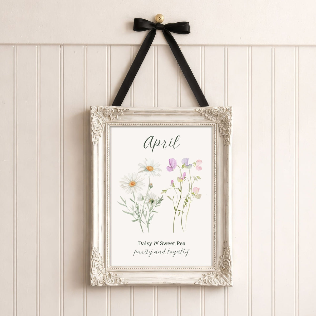 Ornate white framed April birth flower art print with daisies and sweet peas, hanging by a black ribbon.
