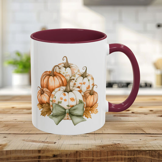 White 11oz ceramic mug with maroon interior/handle, featuring a watercolor pumpkin bouquet and green bow.