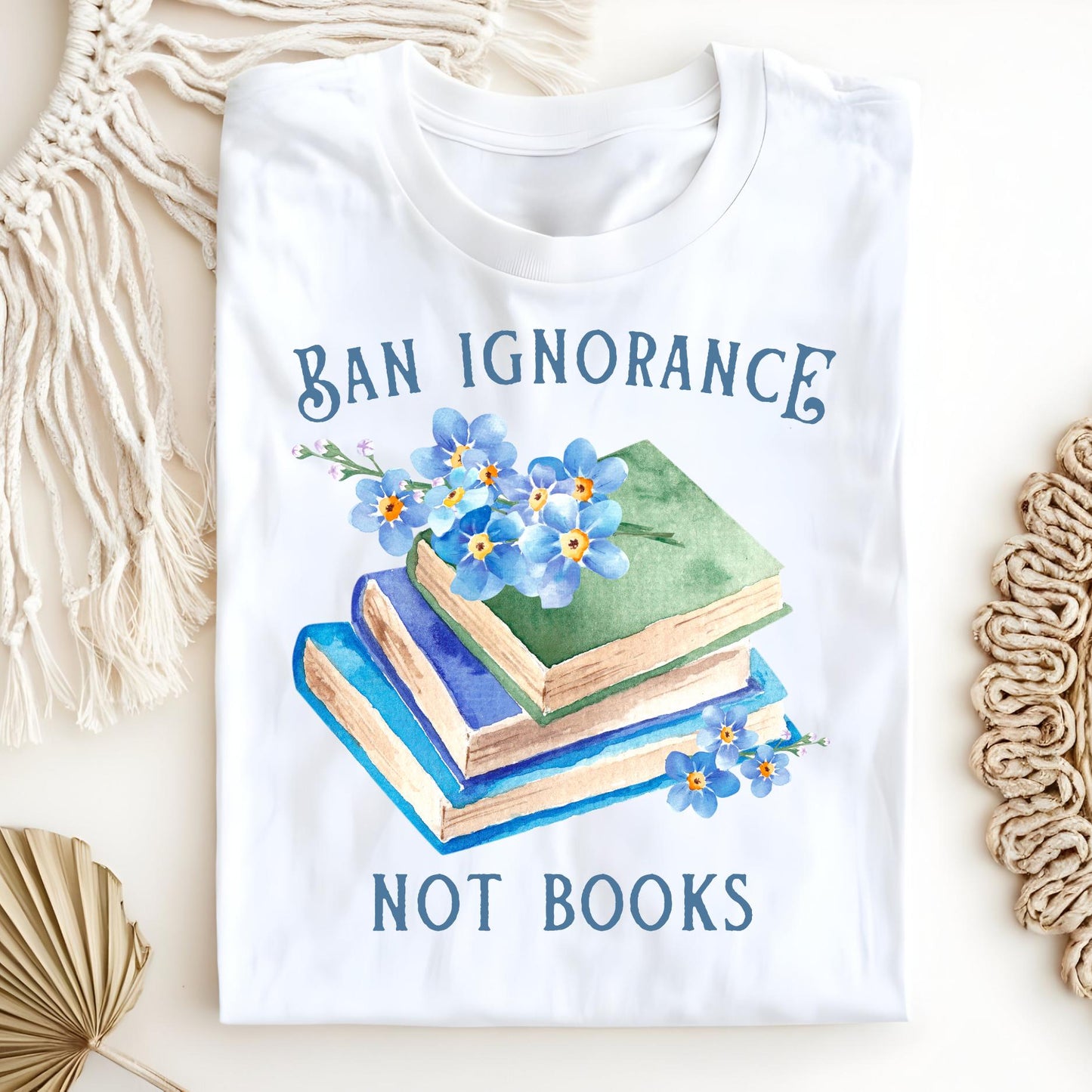 White "Ban Ignorance, Not Books" t-shirt with vintage books and blue watercolor forget-me-nots.