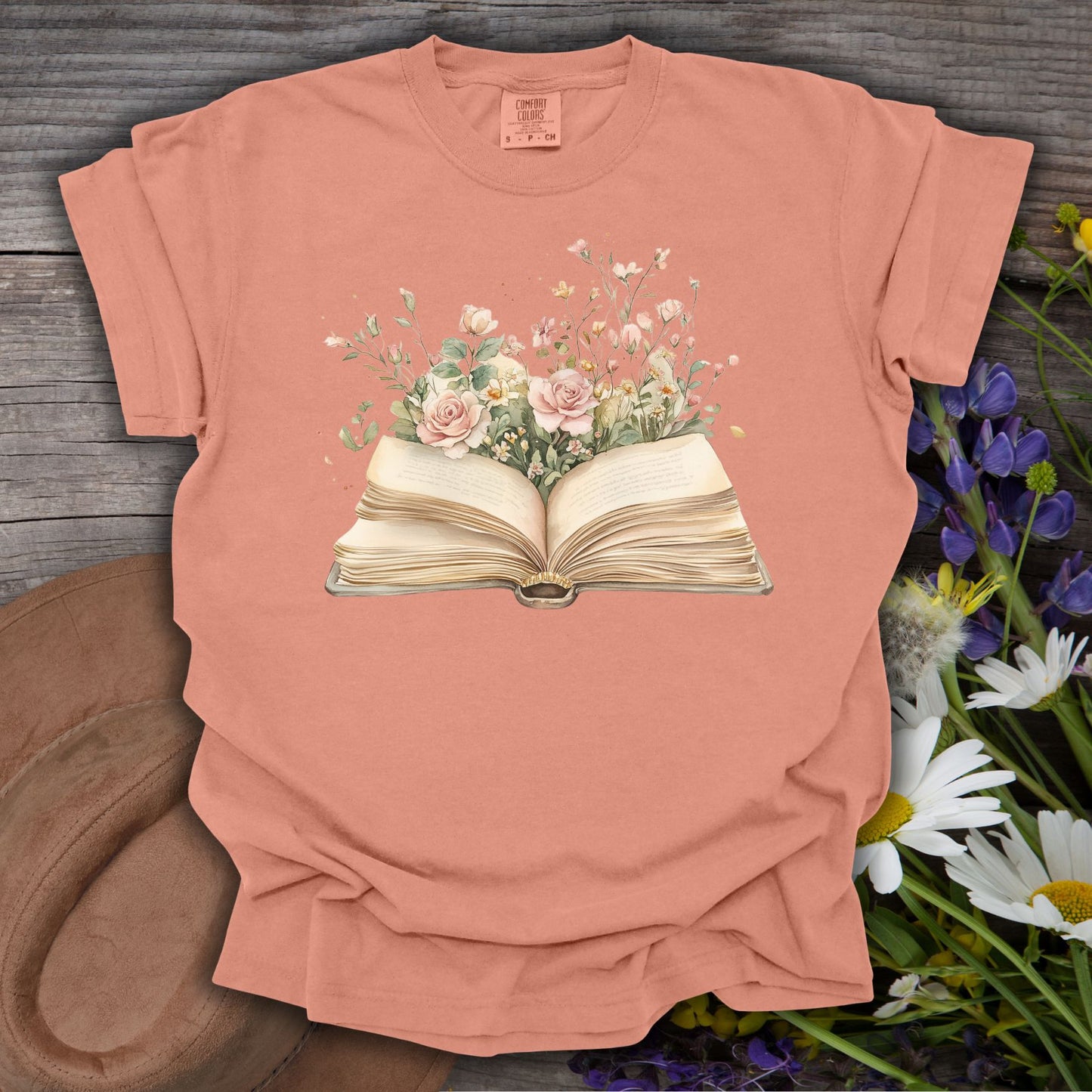 Terracotta S t-shirt with a watercolor illustration of an open book overflowing with pink roses and wildflowers.