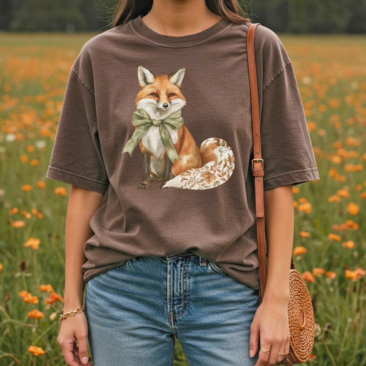 Garment-dyed brown t-shirt with a watercolor fox wearing a sage-green bow and a leaf-patterned tail.