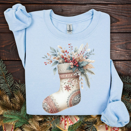 Light blue Gildan sweatshirt with a watercolor boho stocking design overflowing with greenery and berries.
