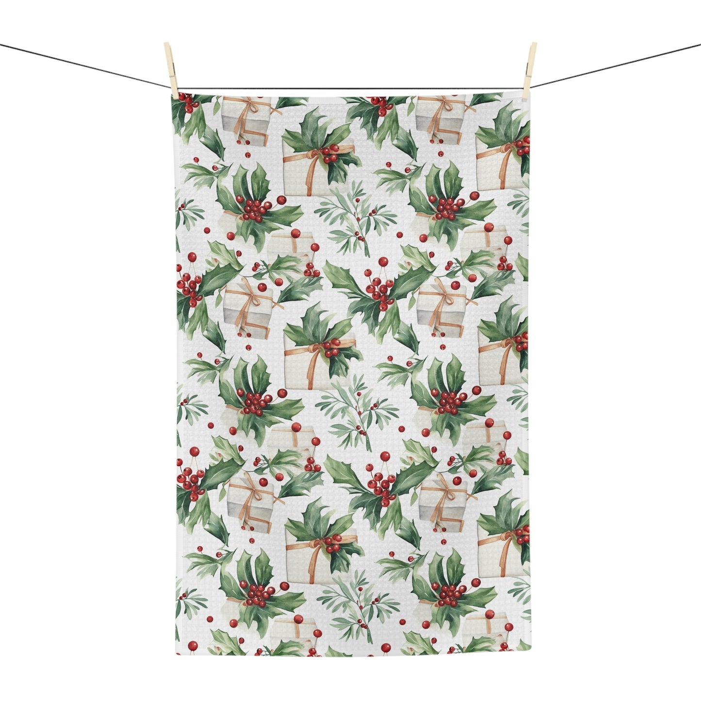 Microfiber tea towel with watercolor holly, red berries, and wrapped gifts, hanging on a clothesline.