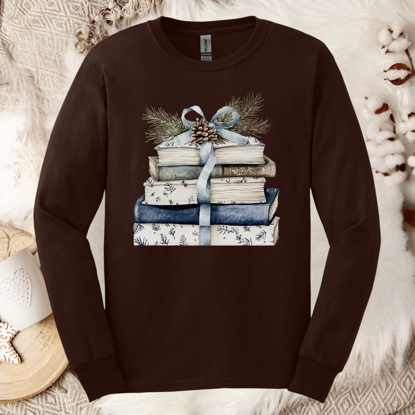 Dark Chocolate long sleeve tee with stacked blue and white books, blue ribbon, evergreen, and pinecone graphic.