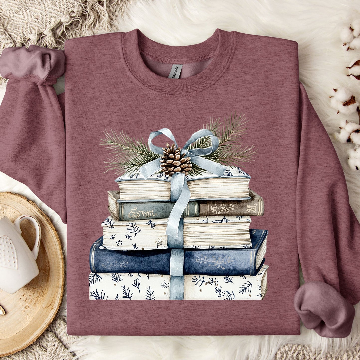 Heather Sport Dark Maroon sweatshirt with a stack of blue and white books, ribbon, evergreen, and pinecone design.