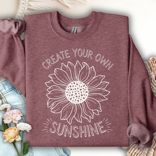 Heather Sport Dark Maroon sweatshirt with a white hand-drawn sunflower and "Create Your Own Sunshine" text.