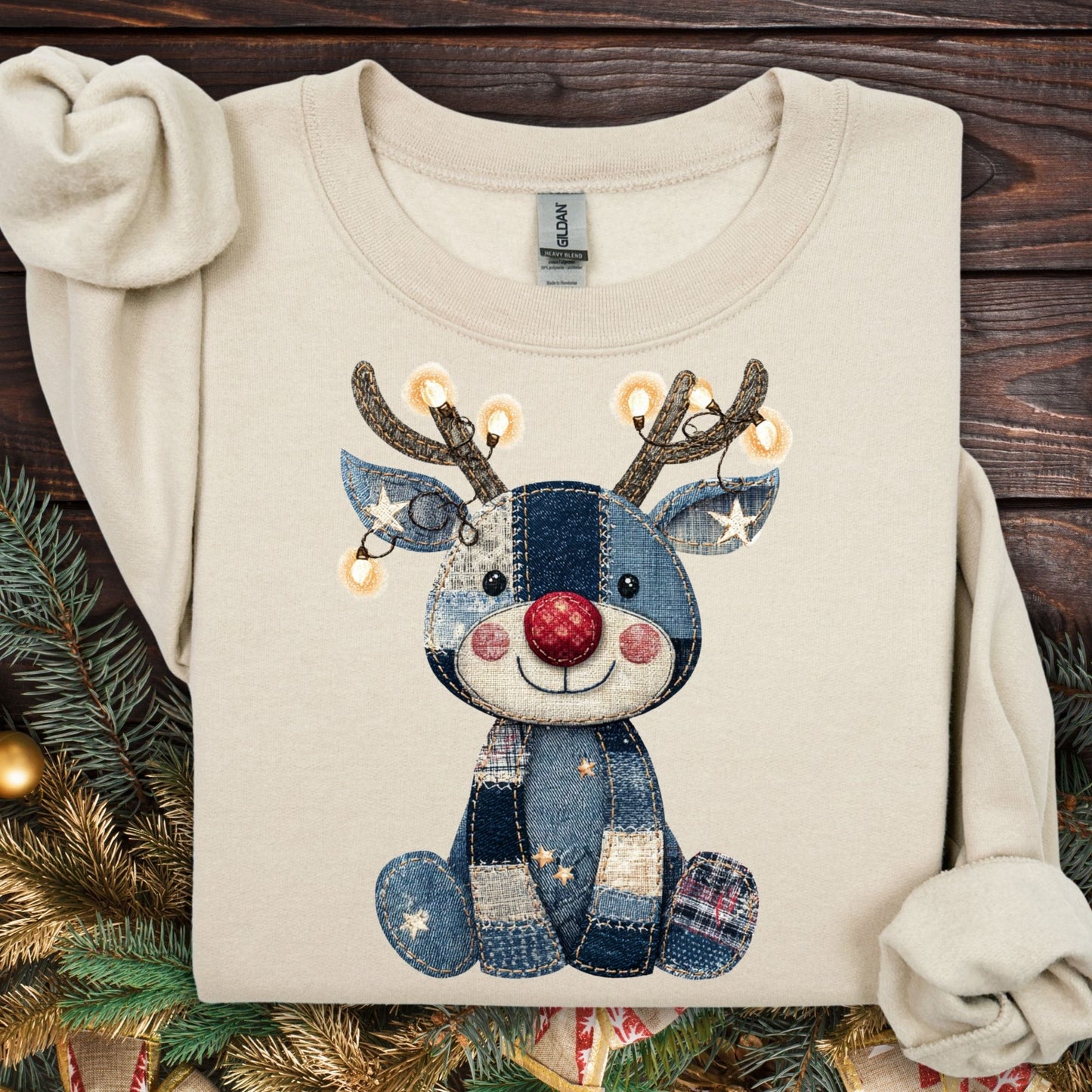 Sand Gildan sweatshirt with a faux denim patchwork baby Rudolph wearing twinkling lights.