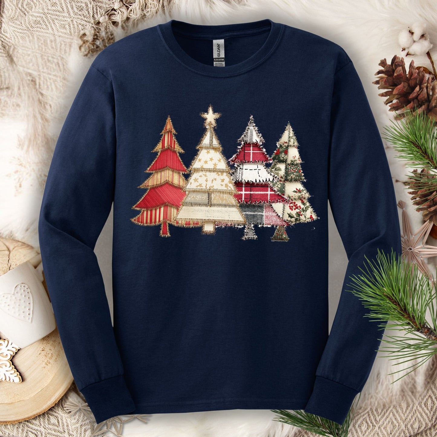 Navy long sleeve tee with a rustic faux patchwork Christmas tree design in reds, greens, and neutrals.