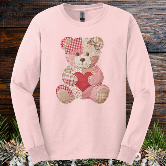 Light pink long-sleeve tee with a faux patchwork teddy bear holding a red heart.
