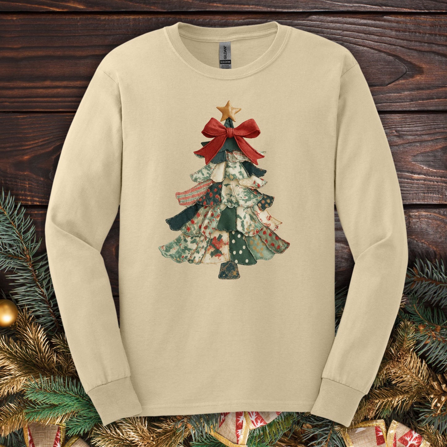 Sand long sleeve tee with a cottagecore patchwork Christmas tree design, red bow, and gold star.