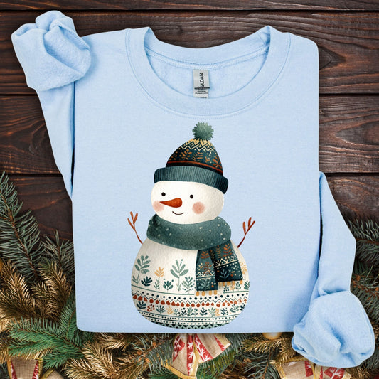 Light blue Gildan crewneck sweatshirt with a folk art snowman in a teal hat and scarf.