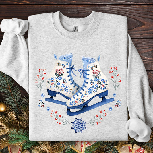 Ash S sweatshirt with folk art ice skates, blue, white, red floral embroidery, and winter greenery.