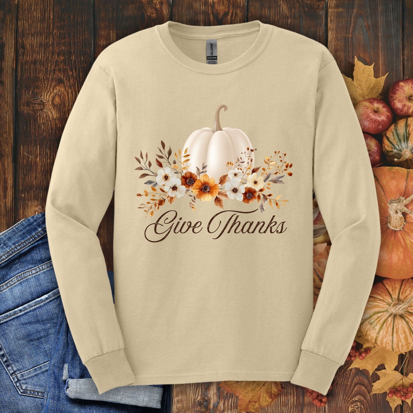 Sand Gildan long sleeve tee with a watercolor white pumpkin, autumn foliage, and "Give Thanks" text.