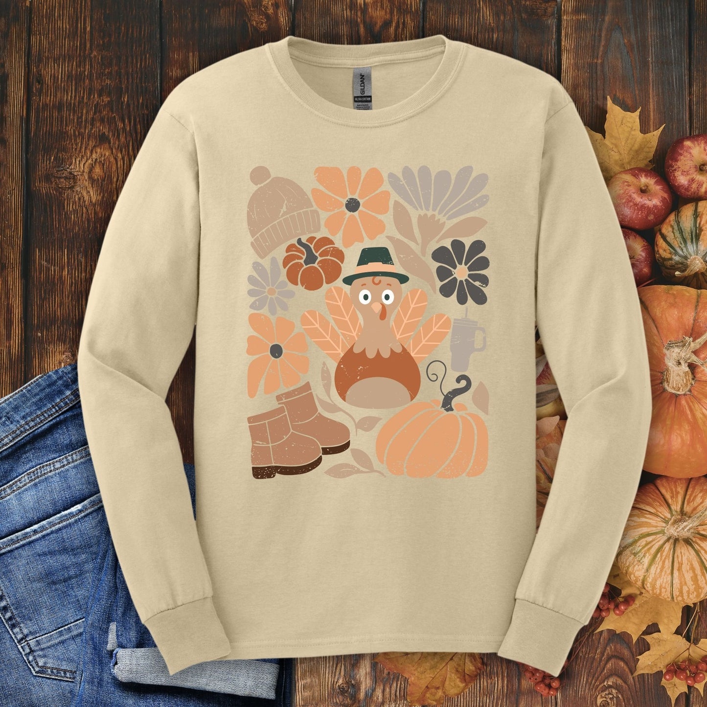 Sand Gildan 2400 long sleeve tee with a "Groovy Turkey" graphic, surrounded by fall boots, leaves, and pumpkins.