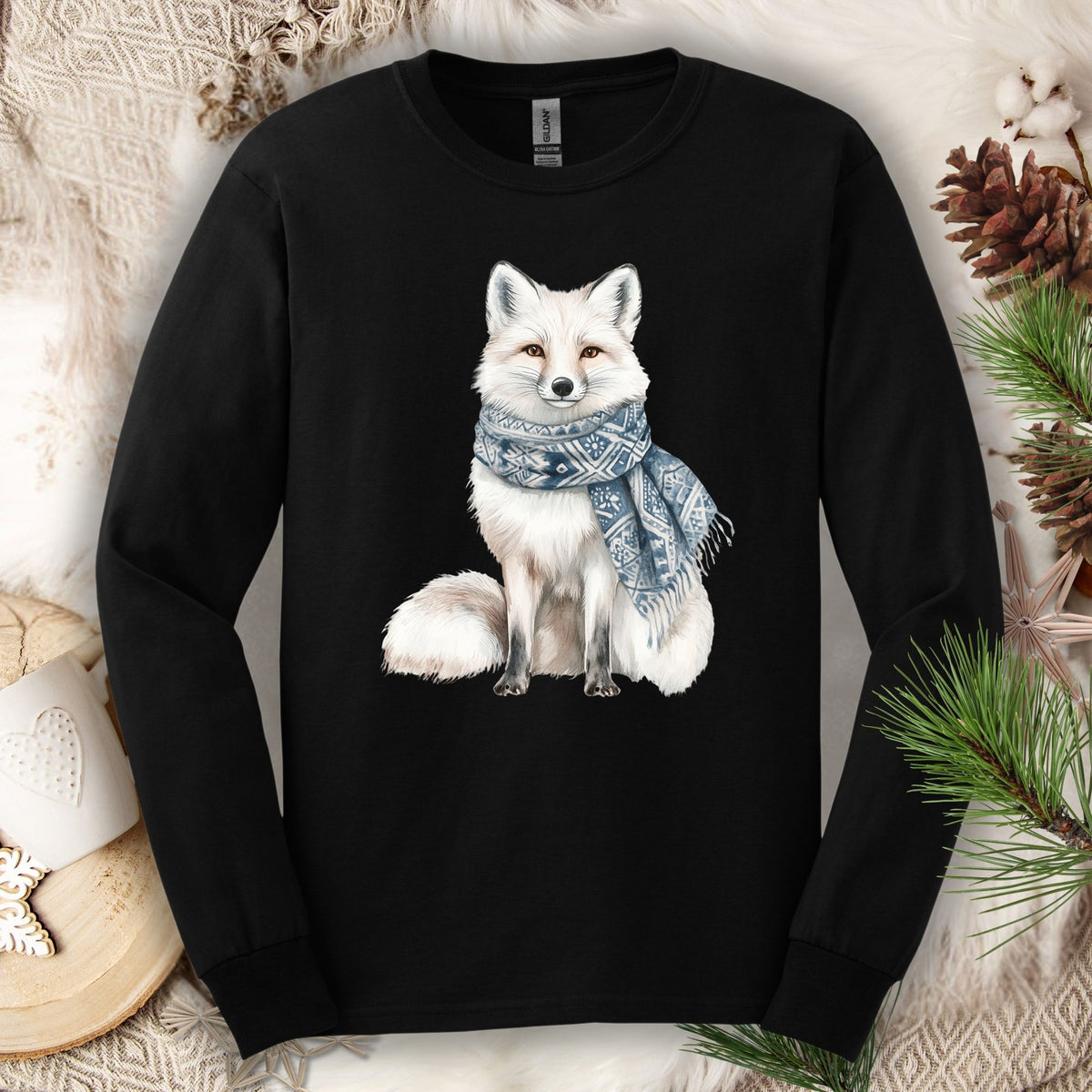 Black long-sleeve tee with a hand-drawn white fox wearing a blue patterned scarf, surrounded by winter decor.