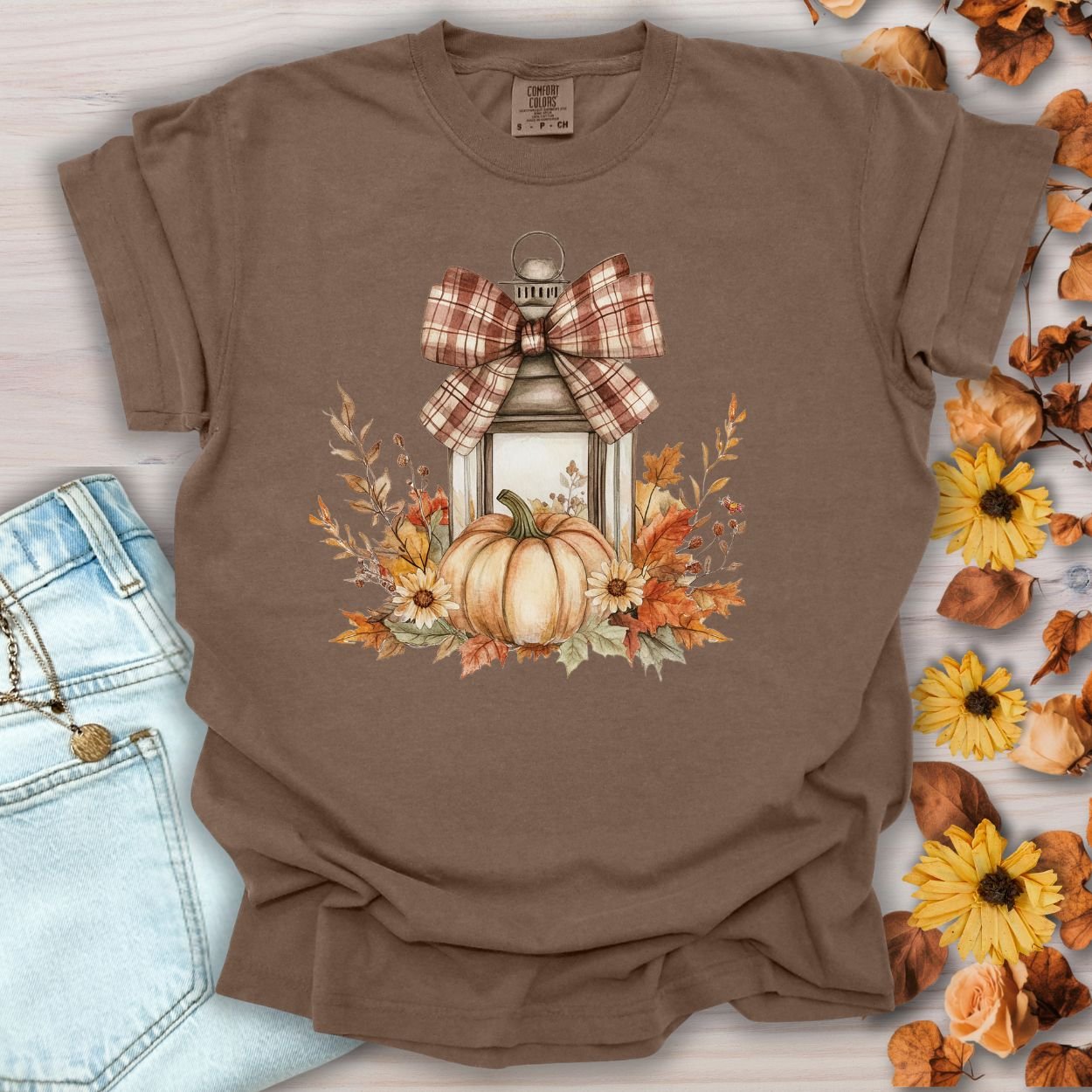 Espresso garment-dyed tee with a rustic lantern, plaid bow, pumpkin, and autumn floral design.