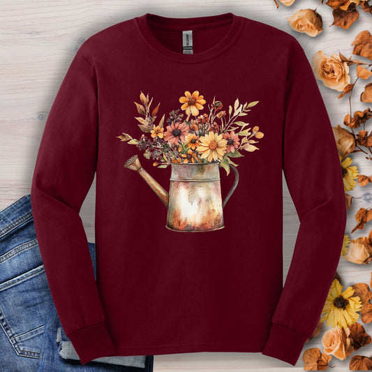 Maroon long sleeve tee with a vintage watercolor watering can overflowing with autumn wildflowers.