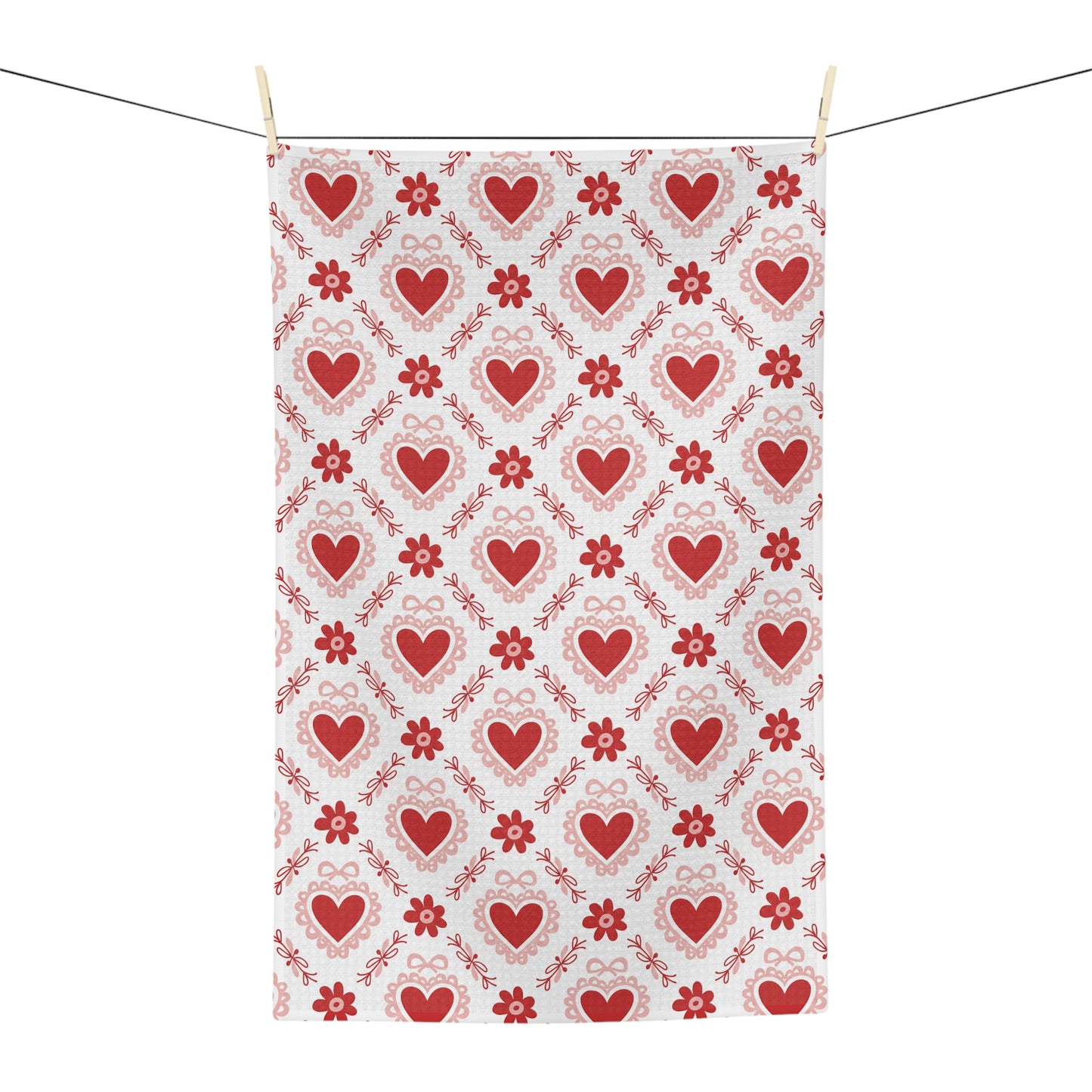 Microfiber tea towel with a repeating pattern of red hearts and small floral motifs, hanging on a clothesline.