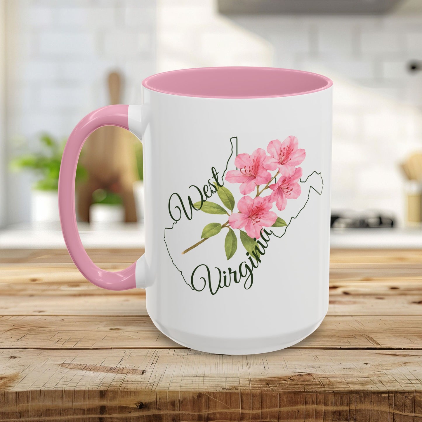 White ceramic mug with pink handle and interior, featuring a watercolor rhododendron and "West Virginia" text over a state silhouette.