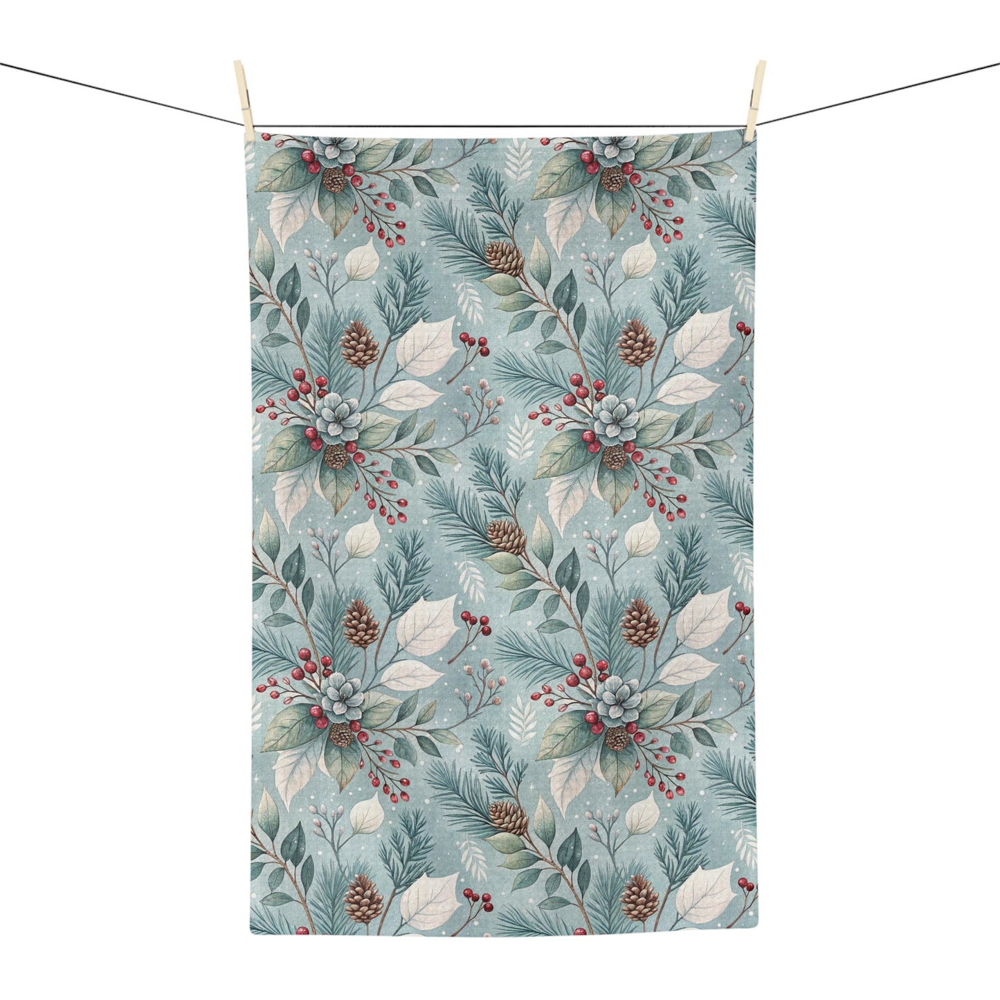 Microfiber tea towel with a repeating winter foliage pattern of teal sprigs, frosted leaves, pinecones, and red berries.