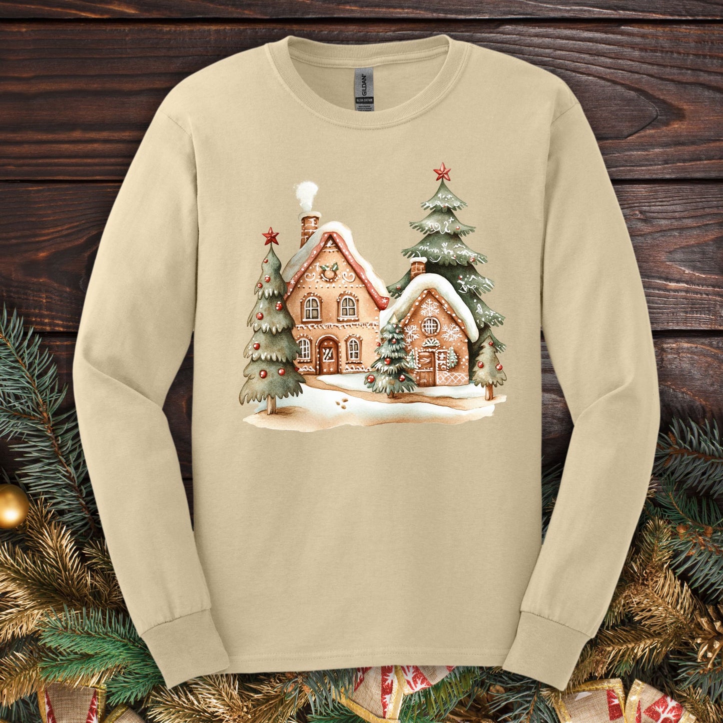 Sand Gildan 2400 long sleeve tee with watercolor gingerbread homes, evergreens, and snow design.