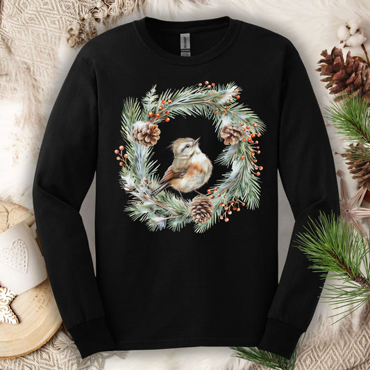 Black long sleeve tee with a watercolor winter wren in an evergreen wreath with pinecones and berries.