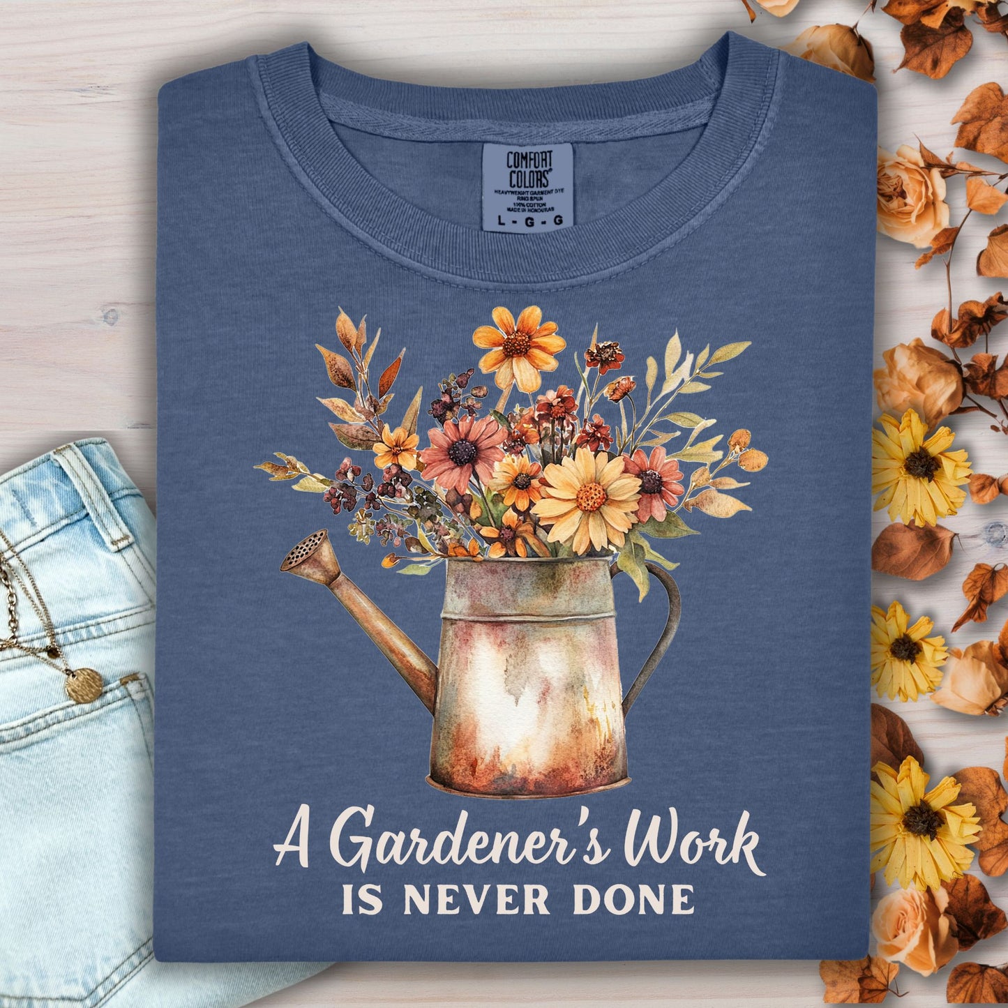Navy Comfort Colors t-shirt with a watering can full of fall flowers and "A Gardener's Work is Never Done" text.