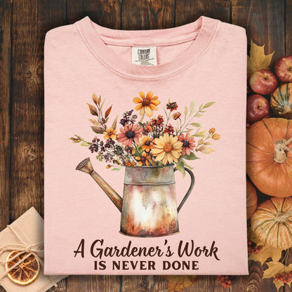 Peachy Comfort Colors t-shirt with a watering can full of fall flowers and "A Gardener's Work Is Never Done" text.