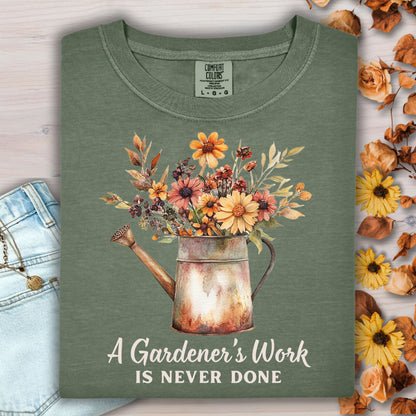 Moss green Comfort Colors t-shirt with a watering can full of autumn flowers and "A Gardener's Work Is Never Done" text.