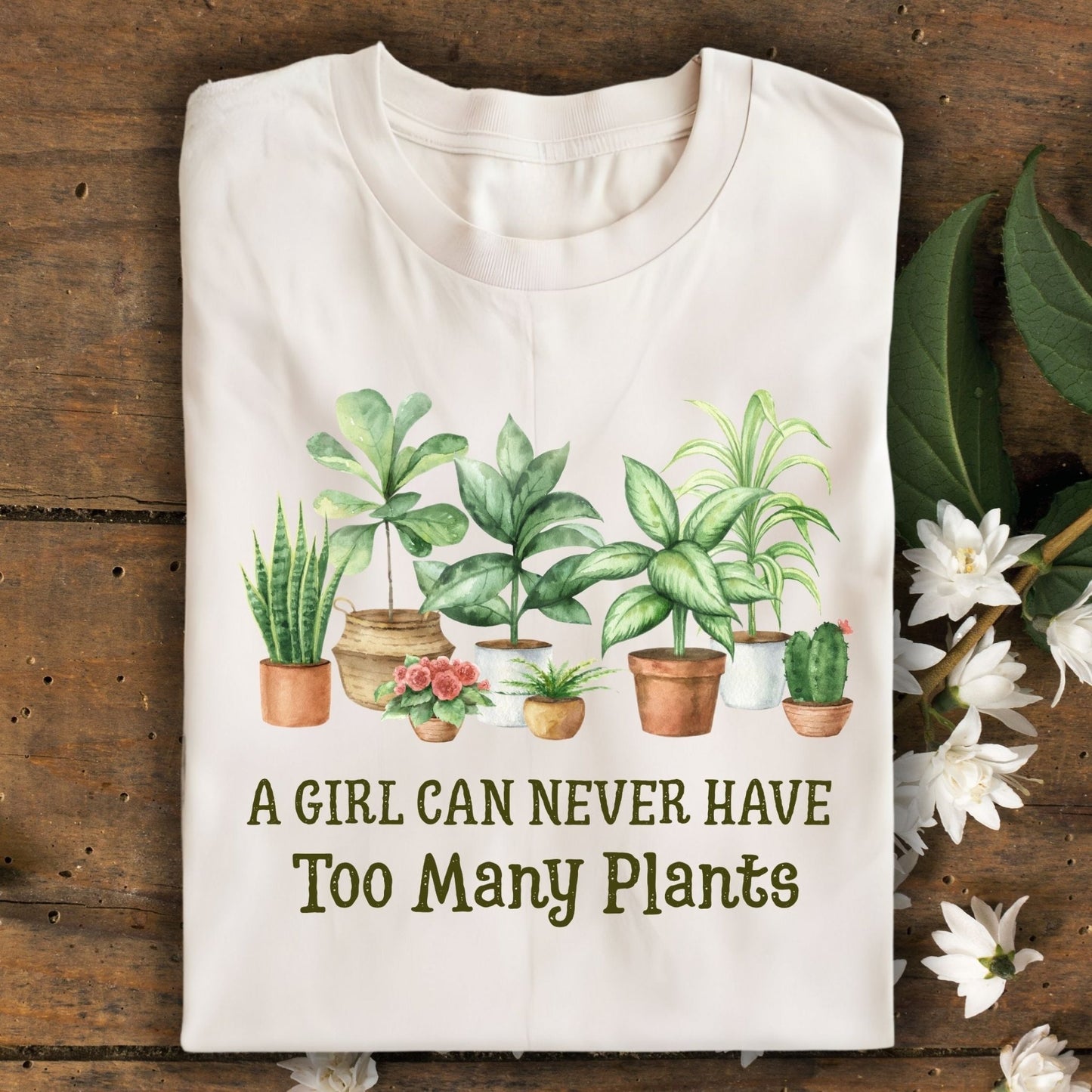 Natural S-size tee with "A Girl Can Never Have Too Many Plants" text and watercolor houseplant art.