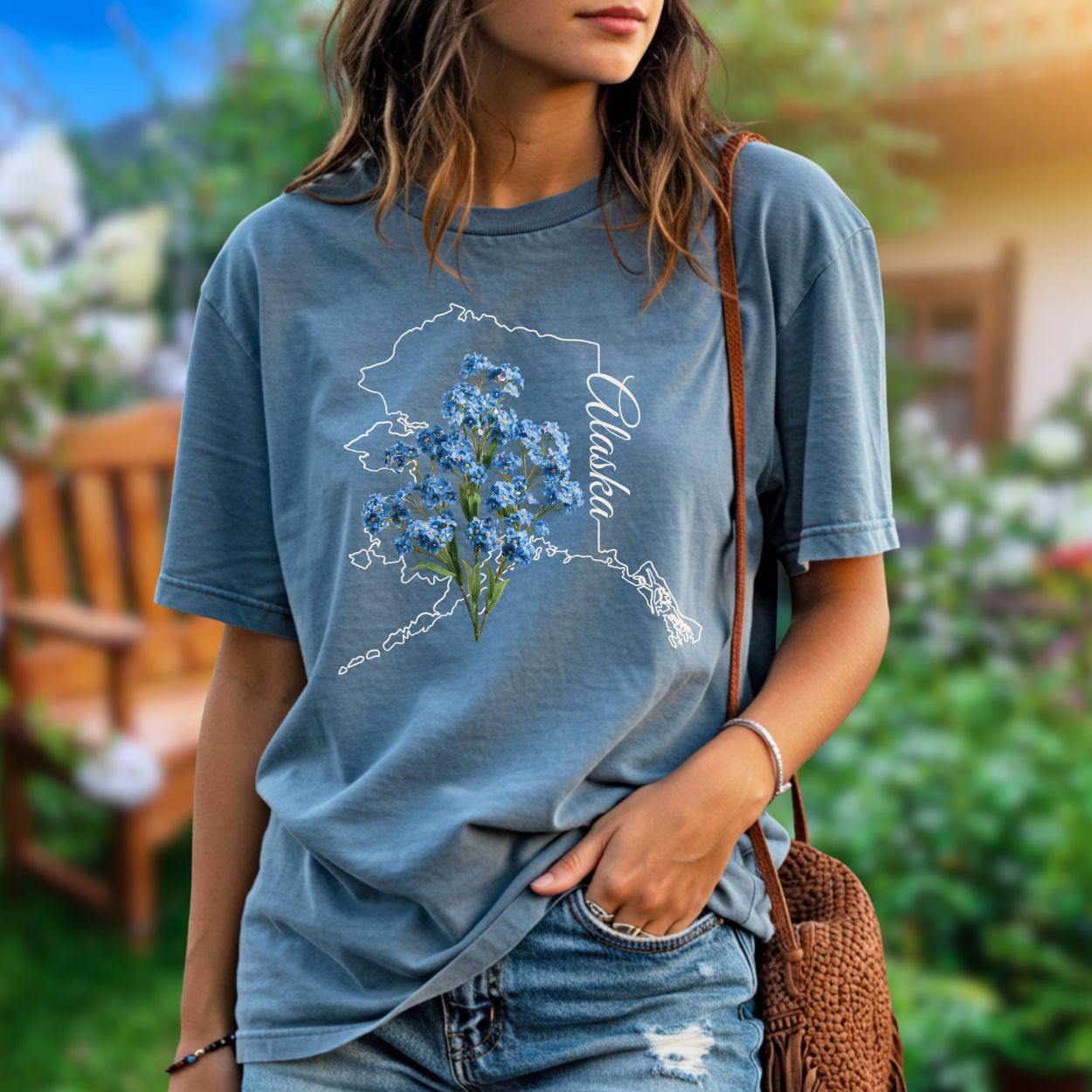 Garment-dyed blue t-shirt with an outline of Alaska and blue forget-me-not flowers.