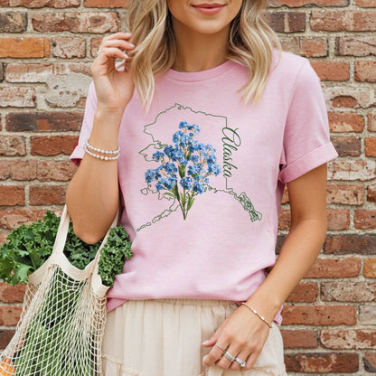 Pink garment-dyed t-shirt with an Alaska outline and blue forget-me-not flowers.