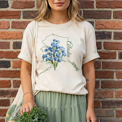 Relaxed-fit, garment-dyed tee with green Alaska outline and blue forget-me-not flowers.