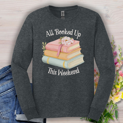 Dark heather long sleeve tee with "All Booked Up This Weekend" text and pastel book stack with flowers.