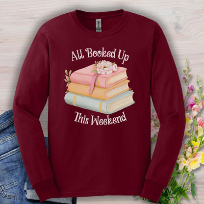 Maroon long sleeve tee with "All Booked Up This Weekend" text and pastel book stack with a sleepy cat.