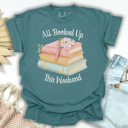 Blue Spruce garment-dyed t-shirt with "All Booked Up This Weekend" text and pastel book stack with flowers.