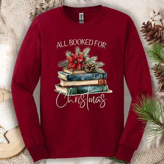 Cardinal Red long sleeve tee with "All Booked for Christmas" text and a watercolor stack of books with poinsettia.