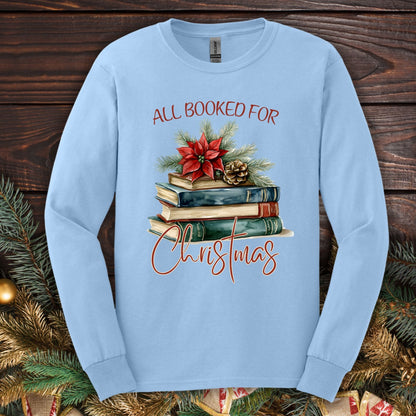 Light blue long sleeve tee with "All Booked for Christmas" text and a watercolor stack of books with poinsettia.