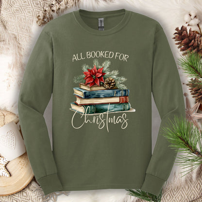 Military green long sleeve tee with a vintage watercolor stack of books, poinsettia, and "All Booked for Christmas" text.