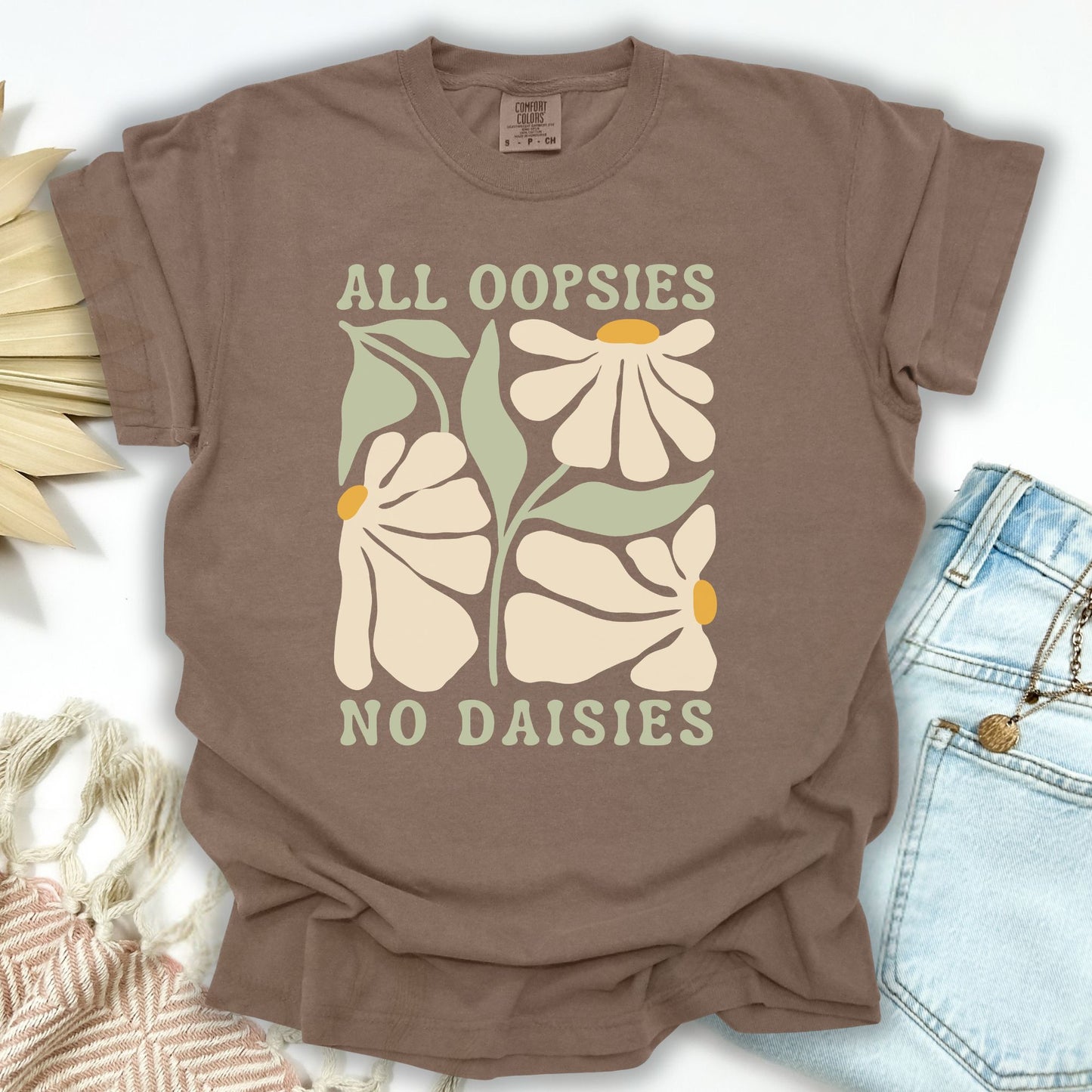 Espresso garment-dyed cotton t-shirt with "All Oopsies No Daisies" text and retro floral design.