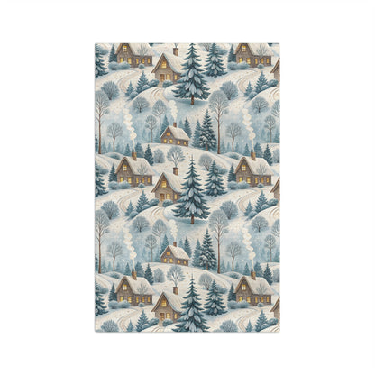 Microfiber tea towel with a muted blue and ochre Alpine winter village scene, featuring cozy cottages and frosted pines.
