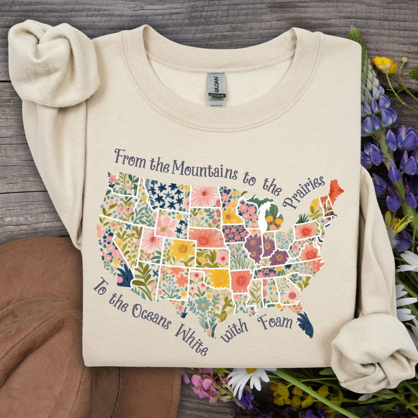 Sand crewneck sweatshirt with a watercolor floral map of the USA and "From the Mountains to the Prairies" text.