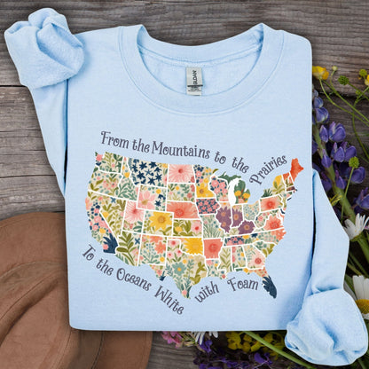 Light blue crewneck sweatshirt with a watercolor floral map of the USA and "America the Beautiful" script.