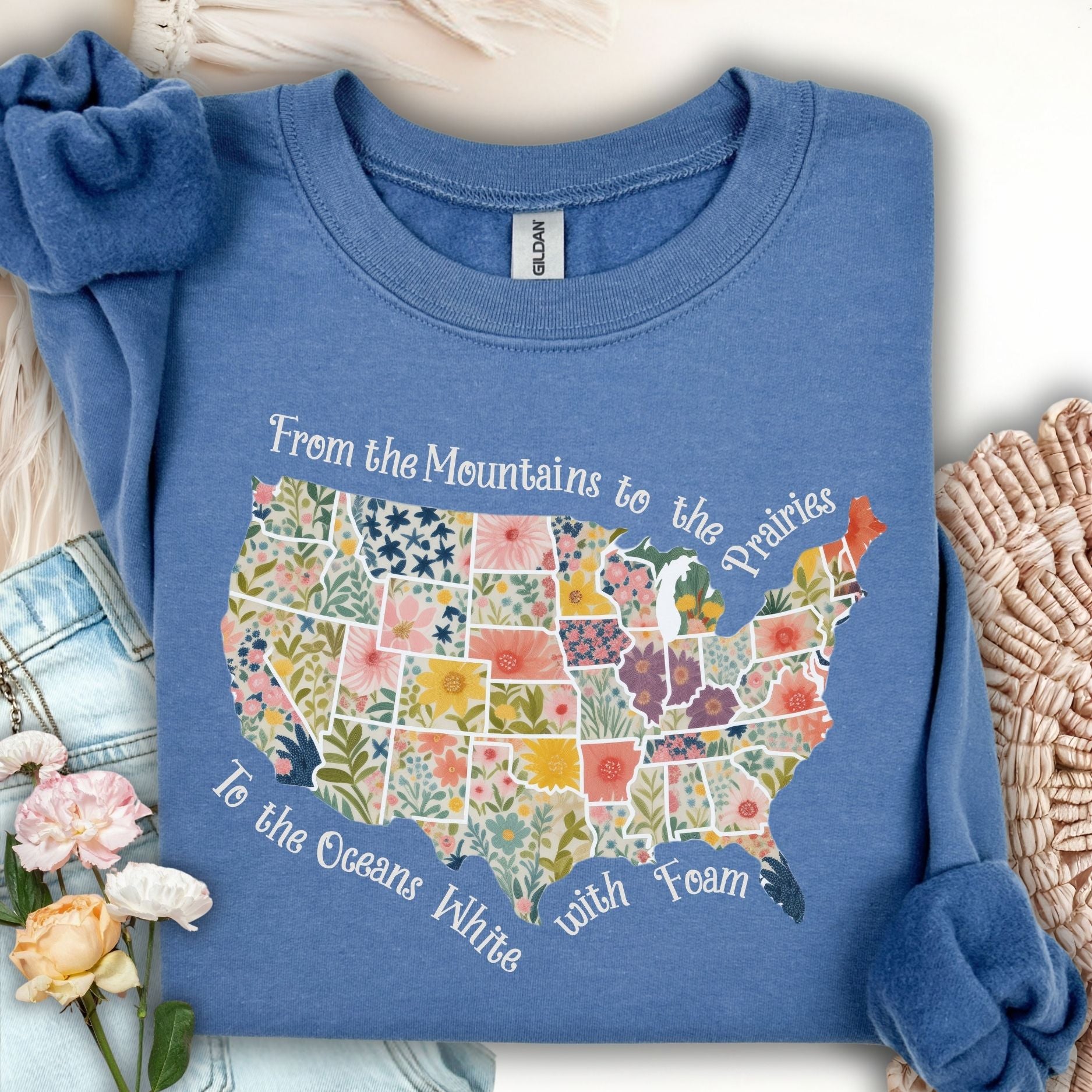 Indigo blue crewneck sweatshirt with a floral watercolor US map and "From the Mountains to the Prairies..." text.