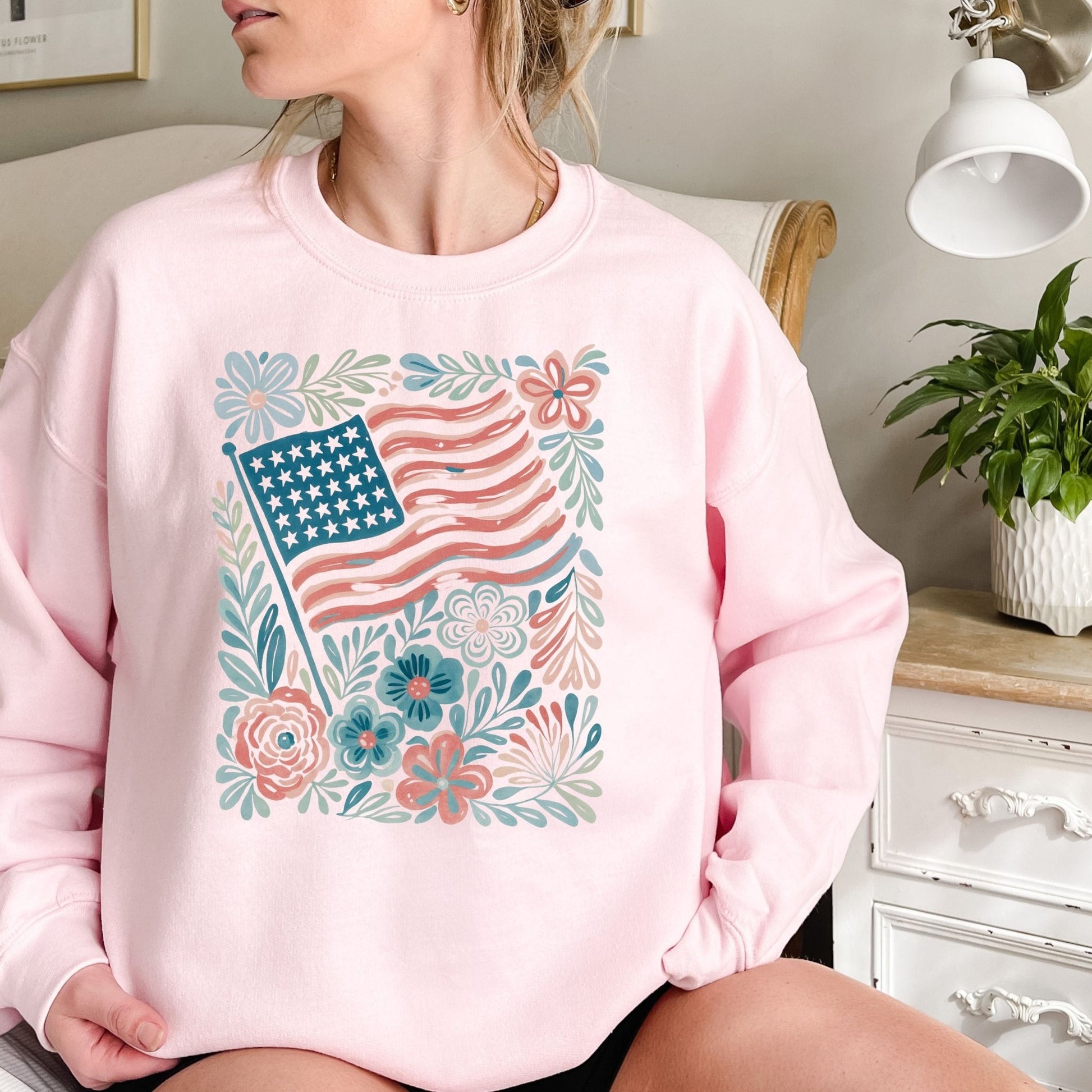 Pink crewneck sweatshirt with a watercolor American flag and floral design.