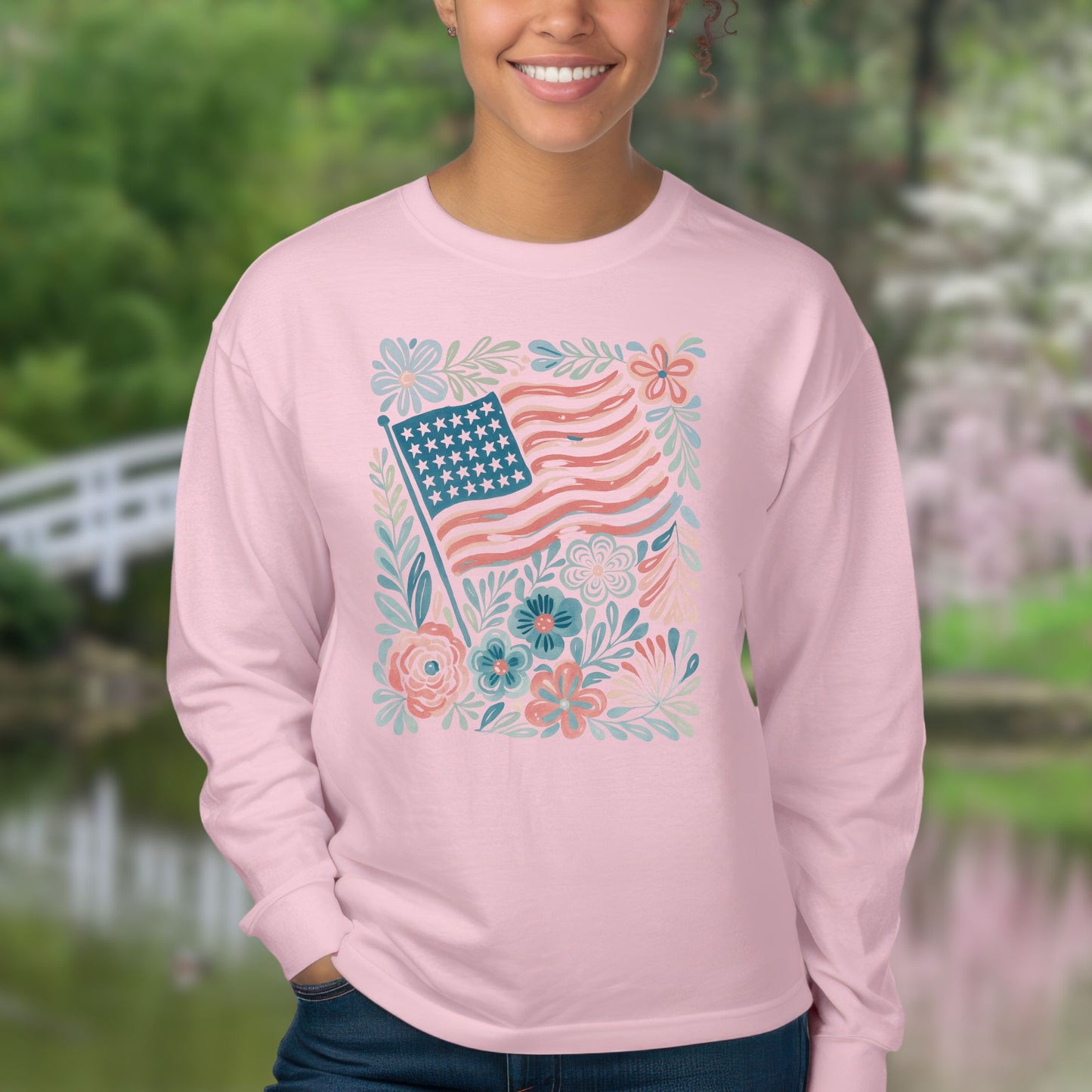 Pink long sleeve tee with a muted red and blue American flag surrounded by hand-drawn flowers and leafy flourishes.