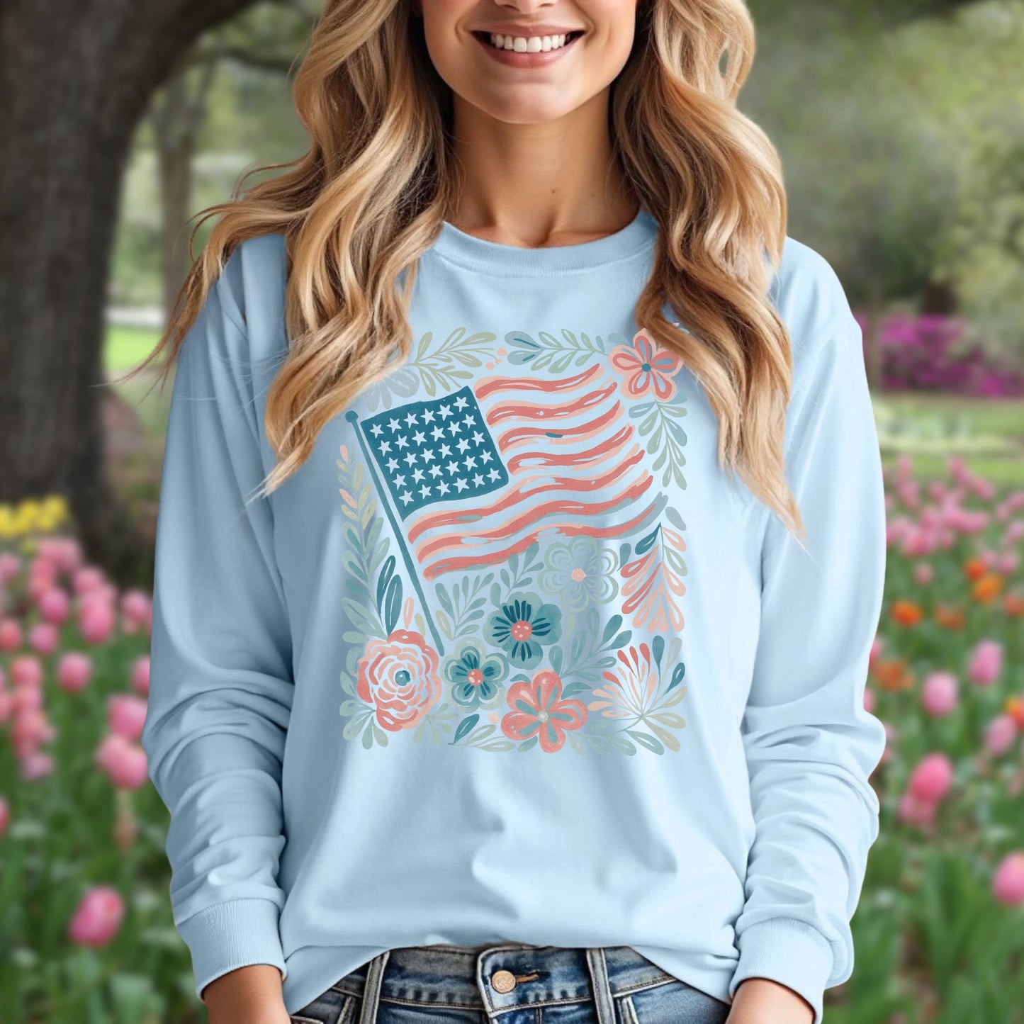 Light blue long sleeve tee with a vintage American flag and hand-drawn floral design, worn by a smiling woman.
