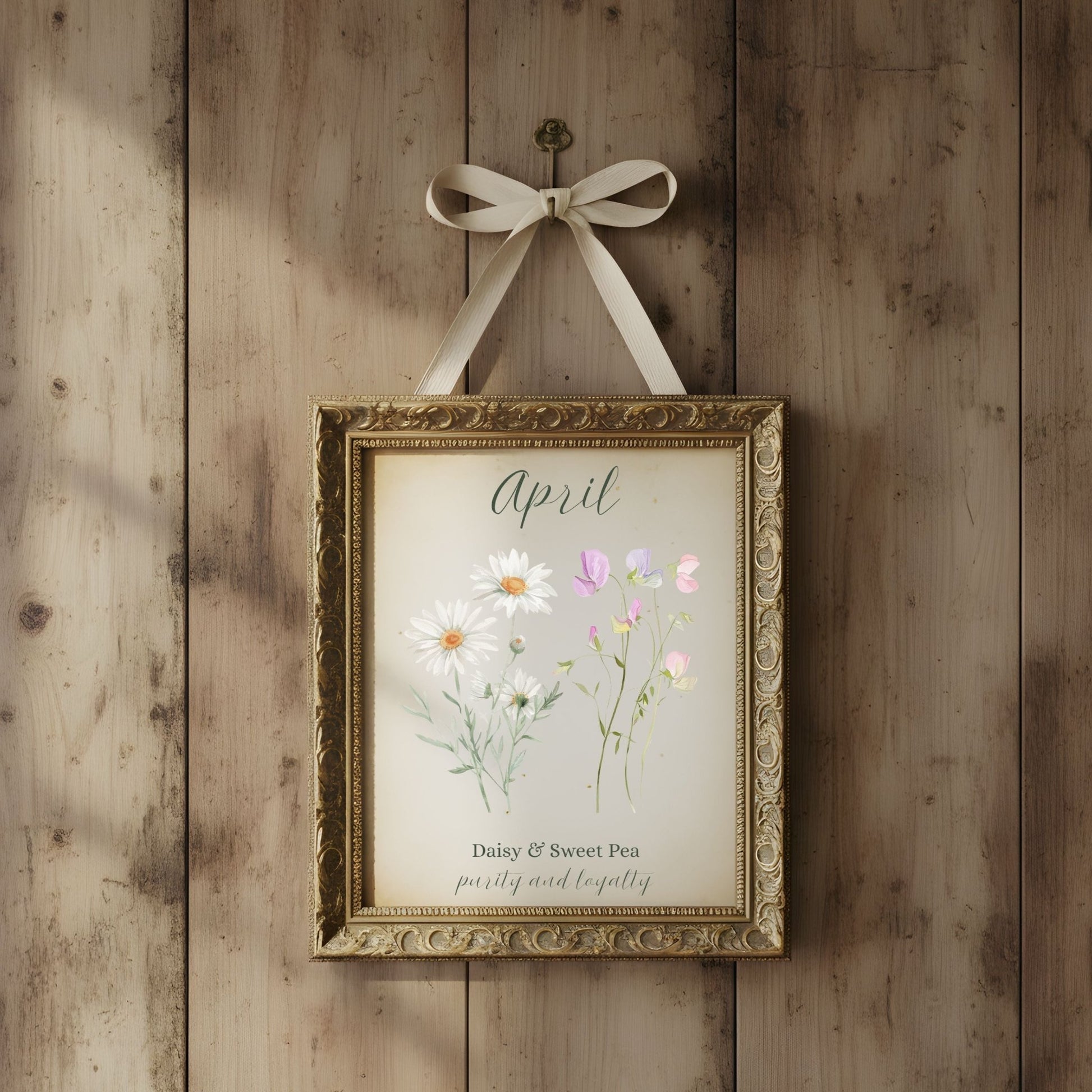 Ornate gold-framed April birth flower art print with daisies and sweet peas, hanging on a rustic wooden wall.