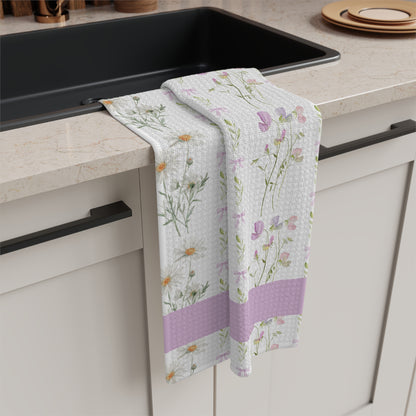 White microfiber tea towel with watercolor daisies, sweet pea blooms, and a lavender stripe, draped over a kitchen counter.